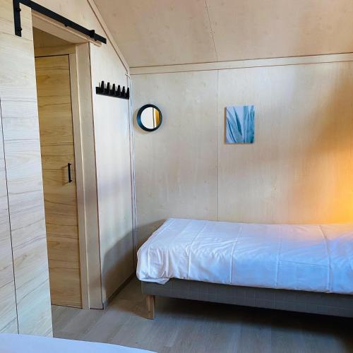 a small bedroom with a bed and a mirror at Osensjøen Camping in Valmen