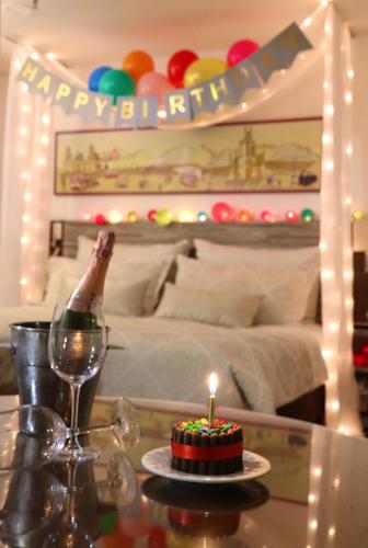 a bottle of champagne and a cake with a candle on a table at Hotel Vilar América in Bogotá