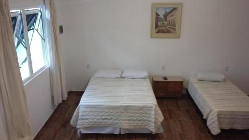 2 camas en una habitación con ventana en BANGALÕ DO LAGO en Caconde