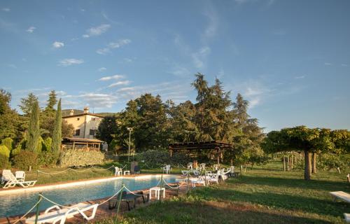 a pool with tables and chairs next to a house at Agriturismo Sasso Rosso in Capodacqua