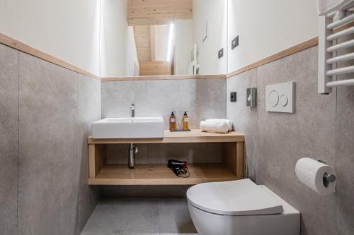 a bathroom with a white toilet and a sink at Chalet Alpenrose in Misurina