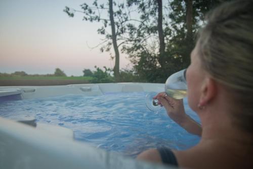 a woman drinking a glass of wine in a tub at Liebevoll hinterm Deich in Lehe