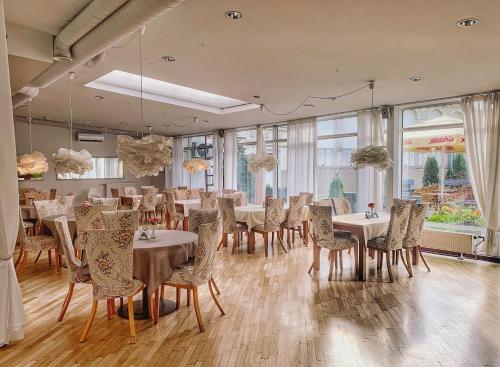 uma sala de jantar com mesas, cadeiras e janelas em NB Hotel with Free Parking em Riga
