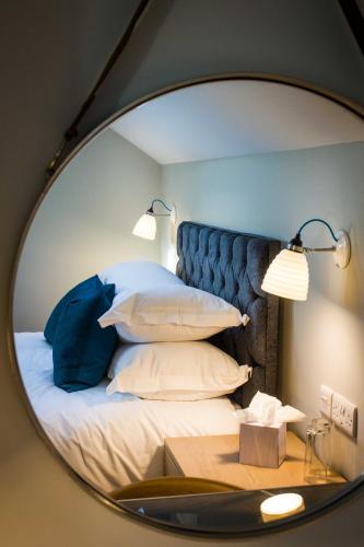 a mirror reflecting a bedroom with a bed with pillows at Crown & Punchbowl in Cambridge