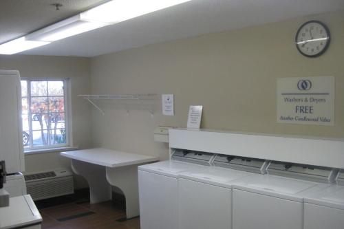 a kitchen with a white counter and a clock on the wall at Candlewood Suites Washington-Dulles Herndon by IHG in Herndon