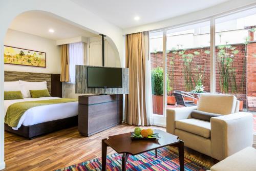a hotel room with a bed and a tv at Suites by Vilar América in Bogotá