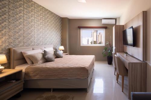 a bedroom with a bed and a desk and a television at Equipetrol Suites apart hotel in Santa Cruz de la Sierra