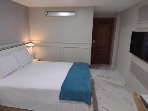 a bedroom with a white bed and a flat screen tv at Antonio's Hotel e Spa - Airport in Brasilia