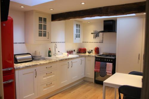 uma cozinha com armários brancos e um frigorífico vermelho em Eagle House - award winning luxury B&B and Apartment em Eccleshall