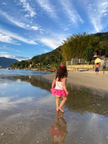 a little girl standing in the water on the beach at A Casa da Ilha de Itacuruçá - Aps in Flecheiras