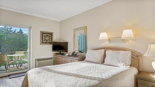 a bedroom with a bed and a television and a patio at Windward Shores in Amagansett