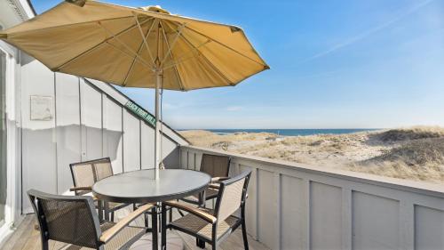 a table and chairs on a balcony with an umbrella at Windward Shores in Amagansett