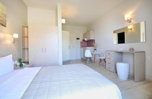 a bedroom with a large white bed and a kitchen at Sirene Villas in Dhiakofti