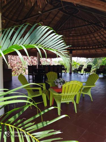 a patio with green chairs and a table and a umbrella at Casa Campo Emaus in Caucasia