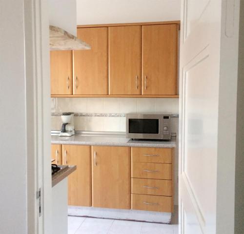 a kitchen with wooden cabinets and a microwave at AL CASA GRANDE in Olhão