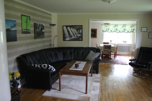 a living room with a black leather couch and a table at Flahult Holiday Home in Hok