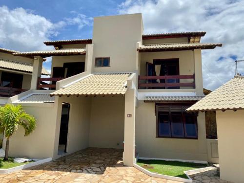 a white house with a palm tree in front of it at CASA BEIRA MAR NA BARRA DE SÃO MIGUEL in Barra de São Miguel