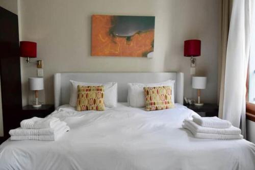 uma cama branca com duas almofadas em cima em 1 Bedroom Apartment with Roof Top Views na Cidade do Cabo