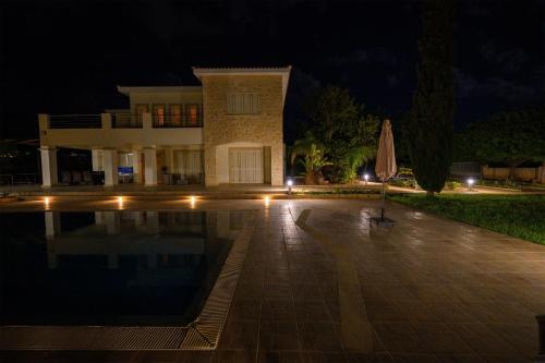 a house with an umbrella in front of a pool at night at Villa Kiki in Peyia