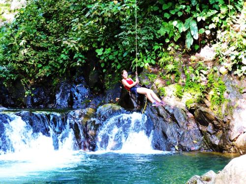 a woman sitting on a swing over a waterfall at Casa Linda Vista in Caño Seco