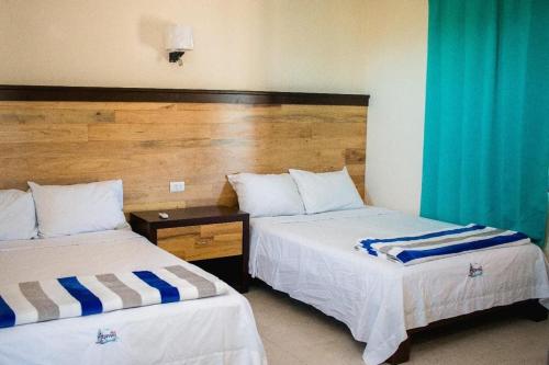 two beds in a hotel room with blue curtains at Apartamento Akamay 2 in El Cuyo