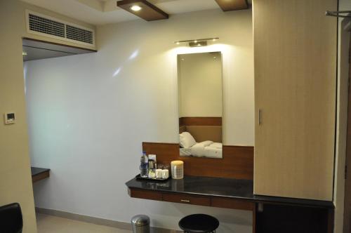 Habitación con baño con espejo y lavabo. en Hotel The Nook, en Madurai