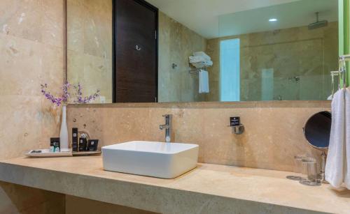 W łazience znajduje się biała umywalka i lustro. w obiekcie GHL Hotel Barranquilla w mieście Barranquilla