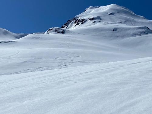 a snow covered hill with a mountain in the background at Haus Maschol in Wald am Arlberg