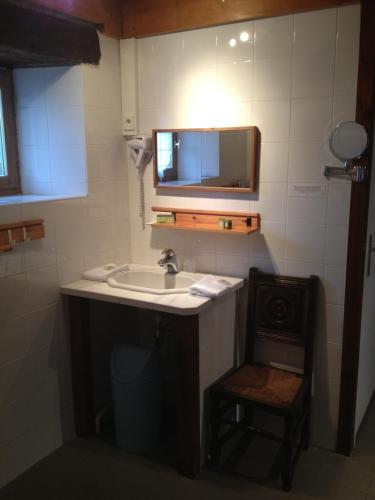 une salle de bain avec un lavabo, un miroir et une chaise dans l'établissement Les Chambres d'hôtes d'Adèle, à Quemper-Guézennec