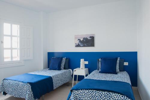 two beds in a room with blue walls at Blancazul Harbour View in Playa Blanca