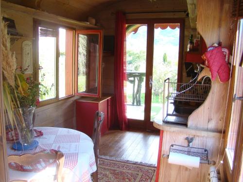 a room with a table and a room with windows at Les Patins à Roulottes in Yenne