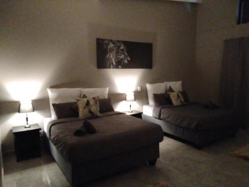 a bedroom with two beds and a couch and two lamps at Fijnbosch Game Lodge Jeffreys Bay in Jeffreys Bay