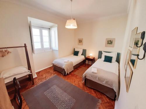 une petite chambre avec deux lits et une fenêtre dans l'établissement Do Campo à Praça, à Golegã