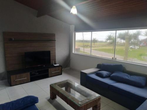 a living room with a blue couch and a tv at Casa temporada Itanhaem in Itanhaém