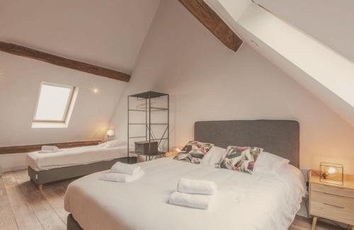 a bedroom with a large white bed in a attic at Domaine Sur Les Sarts in Ohey