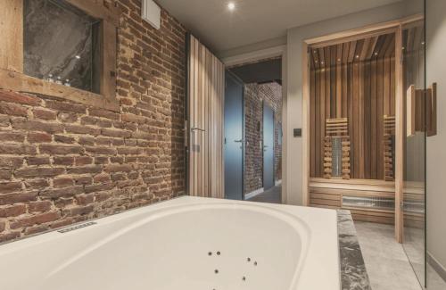 a bath tub in a room with a brick wall at Domaine Sur Les Sarts in Ohey
