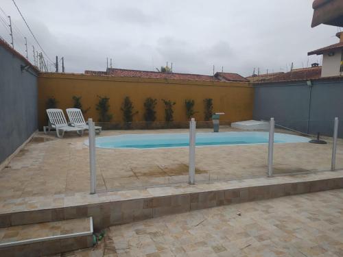 a swimming pool with two chairs in a courtyard at Casa temporada Itanhaem in Itanhaém