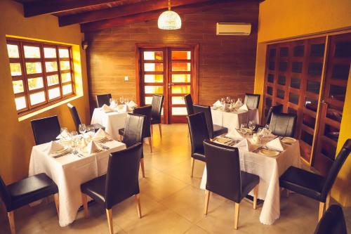 een eetkamer met witte tafels en zwarte stoelen bij Hôtel Regina The Pearl in Aného