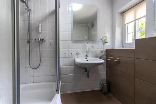 a white bathroom with a sink and a shower at Romantik Hotel Zum Lindengarten in Kurort Jonsdorf