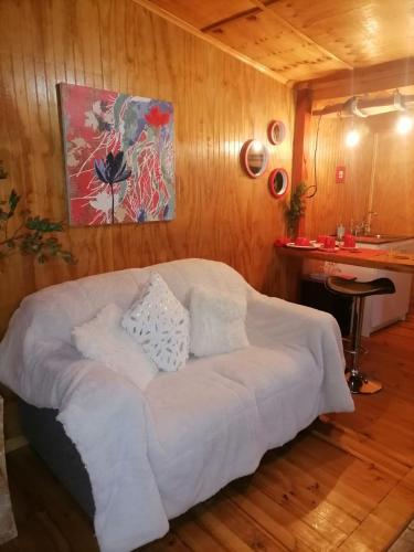 a bedroom with a white bed in a wooden wall at Cabañas Kuela in Puerto Varas
