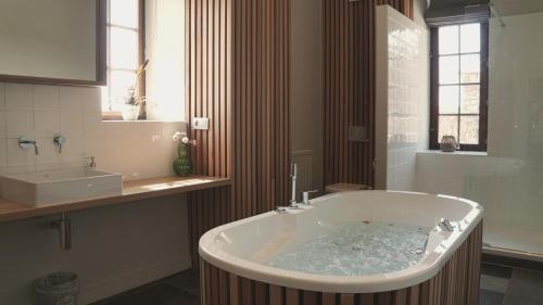 a large tub in a bathroom with a sink at Domaine Sur Les Sarts in Ohey