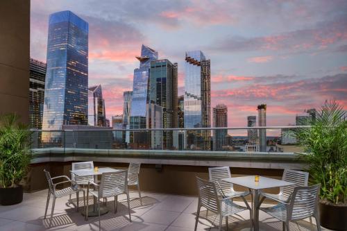 un patio all'ultimo piano con tavoli, sedie e vista sullo skyline della città di DoubleTree by Hilton New York Times Square South a New York