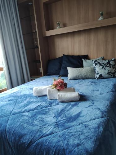 a blue bed with two pillows and flowers on it at Nosso Flat Pedra Azul - Condomínio Vista Azul in Domingos Martins
