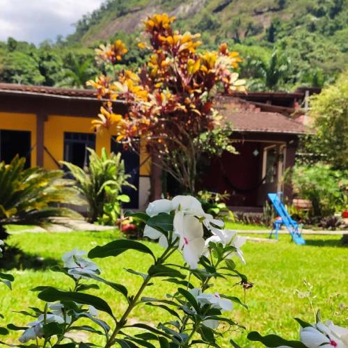 a house with a garden with flowers in the yard at Pousada Nascente Pequena in Guapimirim