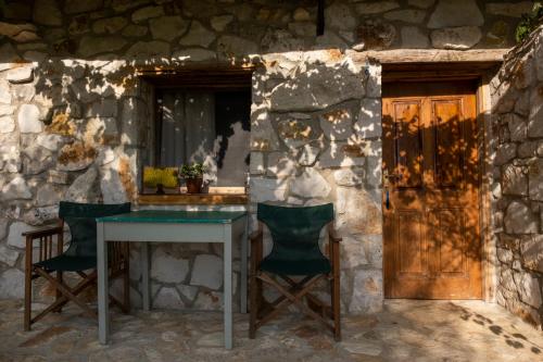 a table and chairs in front of a stone wall at Filoxenia - The Place of Experience in Himare