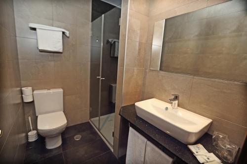 a bathroom with a sink and a toilet and a mirror at Posada La Solana in Santillana del Mar