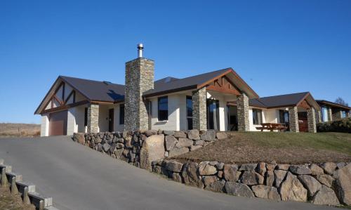 a house with a stone wall and a church at Lake Lodge - Lake Tekapo in Lake Tekapo