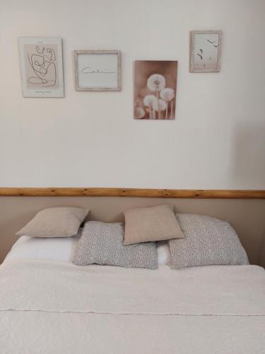a bedroom with a white bed with three pictures on the wall at La Micocoule in La Barben
