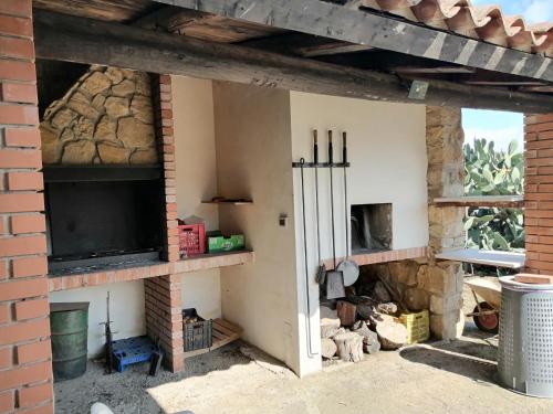 an outdoor fireplace with a television and a brick wall at Villetta immersa nel verde in Piazza Armerina