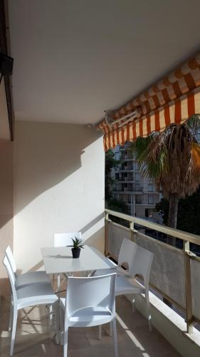 une table et des chaises blanches sur un balcon avec un palmier dans l'établissement Luxe 6 couchages proxi bord de mer centre ville, à Cannes